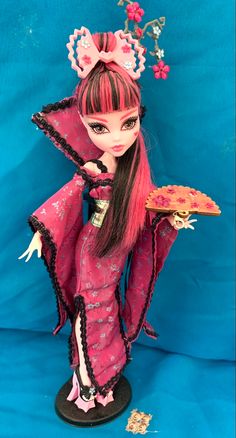 a doll with long hair holding a pizza on a blue background and wearing a pink dress