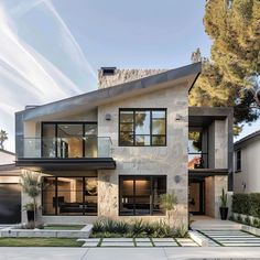 a modern house with large windows and lots of greenery