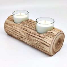 two candles sitting on top of a piece of wood