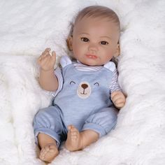 a baby doll laying on top of a white blanket