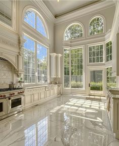 a large kitchen with marble flooring and white walls, windows overlooking the trees outside