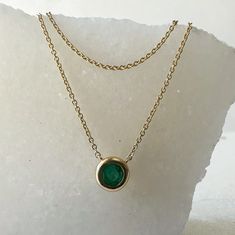 Materials: 14k Gold Gemstone: Emerald Total Emerald Carat Weight: 0.41 ct. Pendant Diameter: 6mm x 6mm Necklace: Adjustable 16, 17, and 18 inches with a lobster clasp. Description: This is natural emerald, not lab grown.  This listing is for one emerald necklace. A beautiful round emerald placed into a bezel setting with a double chain design. Looks like you are wearing a layering necklace with the simplicity of just one necklace! This beautiful piece will not tarnish in the shower and will not irritate the skin. It will arrive in a jewelry box, with a jewelry bag for traveling. Perfect for gift giving! Feel free to message me with any questions! Round Solitaire Necklace With Smooth Bezel As Gift, Round Emerald Necklace In 14k Gold Bezel Setting, Round Bezel Set Emerald Necklace For May Birthstone, Round Bezel Set Emerald Necklace In 14k Gold, Round Emerald Necklace With Bezel Setting For May Birthstone, 14k Gold Round Emerald Necklace With Bezel Setting, Double Chain Necklace, Emerald Necklace, Chain Design