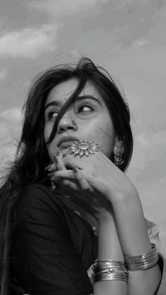 black and white photograph of a woman with bracelets on her neck holding something up to her mouth