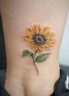 a small sunflower tattoo on the side of a woman's lower back leg