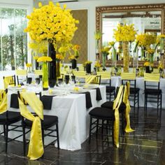 the tables are decorated with black and yellow linens, white tablecloths, and tall centerpieces