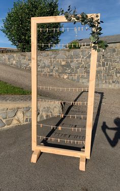 a wooden frame with clothes pegs attached to it and a tree in the background