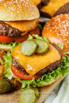 hamburgers with cheese and pickles are on a cutting board, ready to be eaten