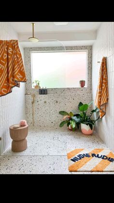 a bathroom with an orange and white rug on the floor next to a toilet in front of a window