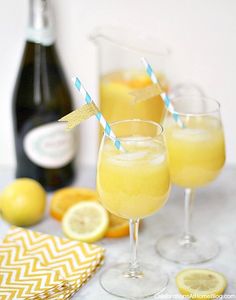 two glasses filled with lemonade sitting next to a bottle