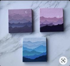 three small canvases with mountains painted in different shades of purple, blue and pink