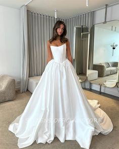 a woman standing in front of a mirror wearing a white wedding dress