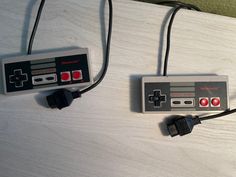 two nintendo game controllers sitting next to each other on a white tablecloth covered surface