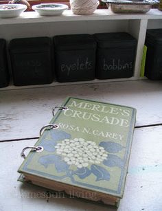 a book sitting on top of a table next to some black boxes and baskets filled with yarn