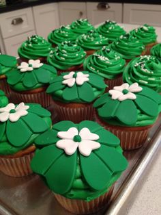 cupcakes with green frosting and white flowers on them sitting on a counter