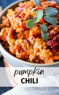 a white bowl filled with pumpkin chili and topped with fresh sage leaves on the side