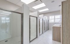 an empty bathroom with white tile and glass doors on the walls is seen in this image