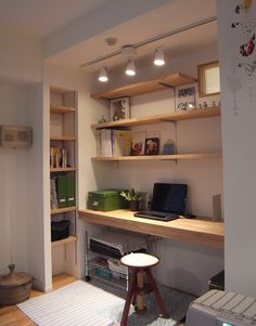 a laptop computer sitting on top of a wooden desk next to a shelf filled with books