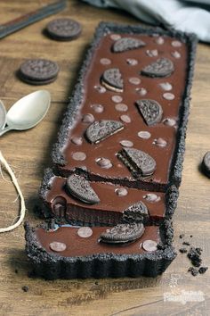 an oreo cookie bar with chocolate frosting and cookies on it next to spoons