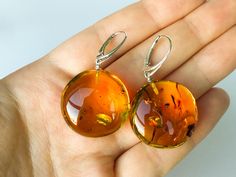 "Bright amber earrings made from round flat cognac color amber beads and silver findings. These orange color gemstone earrings are a perfect example of how organic amber jewelry can make your life happier. Also a great natural amber gift for your loved ones. MATERIALS AND SIZE: Stone: 100% Natural Baltic Amber Findings: Sterling silver 925 Weight: 12 g (0,42 oz) Bead size: 2,7 cm (1,06 in) x 2,7 cm (1,06 in) Total earring lenght: 4,6cm (1,81 in) PLEASE NOTE: All our amber production is made of n Round Baltic Amber Jewelry In Amber Color, Round Baltic Amber Jewelry, Orange Baltic Amber Round Jewelry, Handmade Baltic Amber Orange Jewelry, Cognac Color, Amber Earrings, Earrings Round, Natural Amber, Amber Beads