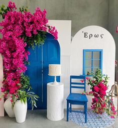 a blue chair sitting next to a white vase with pink flowers on top of it