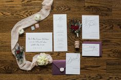 the wedding stationery is laid out on top of the wooden floor with flowers and ribbons