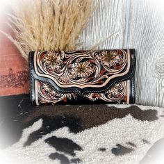 a black and white purse sitting on top of a cowhide rug next to a plant