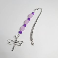 a purple beaded necklace with a dragonfly charm on it's end and a silver hook