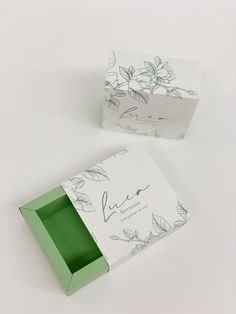 an open green box sitting on top of a white table next to a cardboard box