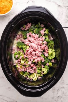 the food in the slow cooker is mixed with meat and broccoli florets