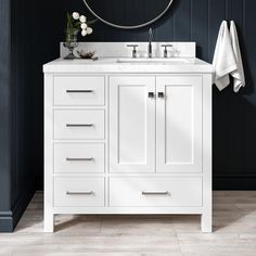 a white bathroom vanity with two sinks and a round mirror over the sink in front of it