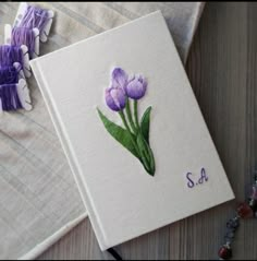 an embroidered book with purple flowers on it