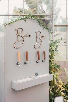 the beer tap sign is decorated with greenery and wooden pegs to hang on the wall