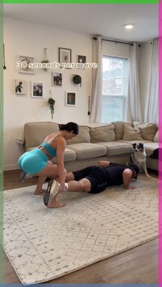 two people are playing with a dog on the floor in front of a living room