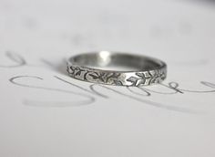 a wedding ring sitting on top of a piece of paper with the word love written in cursive writing