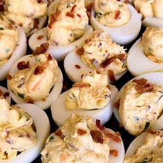 an assortment of deviled eggs with bacon on them