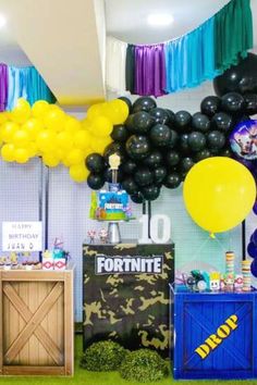 a room filled with balloons and decorations for a fortnite themed birthday party on the grass