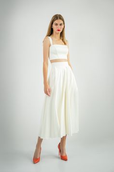 a woman wearing a white skirt and crop top