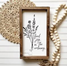 a wooden frame sitting on top of a white wall next to a string of beads