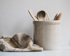 wooden utensils in a ceramic container next to a blanket