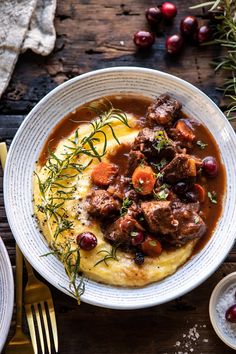 a white bowl filled with meat and gravy on top of mashed potatoes