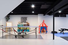 a room with tables, chairs and toys on the floor in front of a white wall