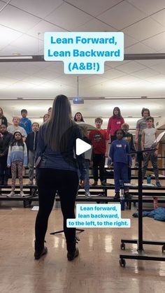 a woman standing in front of a group of people on top of a hard wood floor