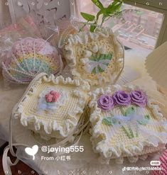 three crocheted baskets with flowers on them sitting on a table in front of a window