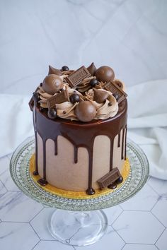 a cake with chocolate icing and nuts on top is sitting on a glass plate