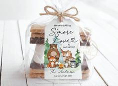 some kind of food wrapped in plastic on top of a white wooden table with a tag that says, smore love enjoy's baby shower