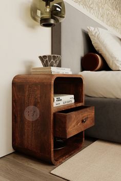 a nightstand with two drawers on top of it in front of a bed and lamp