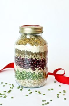 a glass jar filled with lots of different types of food next to a red ribbon