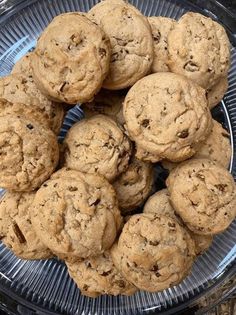 chocolate chip cookies piled on top of each other in a glass bowl, ready to be eaten