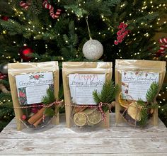 three bags of spices sitting on top of a wooden table next to a christmas tree