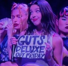 three women are holding signs in front of their faces while one woman holds a sign that says guts please out friday